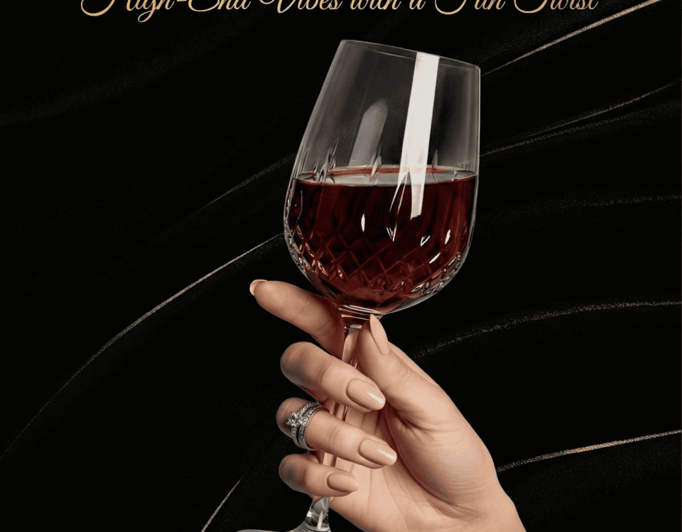 A hand with rings holding a decorative wine glass on a white fabric background.